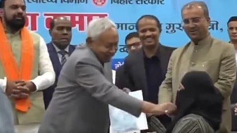 The screengrab from the viral video shows Bihar CM Nitish Kumar removing the hijab of a doctor 