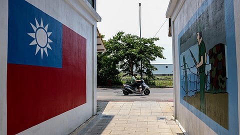 A motorist commutes past paintings on a wall of the Taiwan flag and a soldier in Taiwan's Kinmen on May 18, 2024.