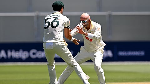 Australian bowler Nathan Lyon (R) celebrates with Mitchell Starc (L) after dismissing England batsman Ben Duckett on the second day of the third Ashes cricket Test match on December 18, 2025.