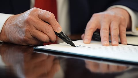 US President Donald Trump signs an executive order in the Oval Office of the White House, Thursday, Dec. 18, 2025, in Washington.