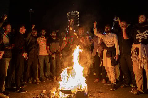 People chant slogans around a fire on a street in Dhaka on December 18, 2025, amid protests following the news of the death of youth leader Sharif Osman Hadi.
