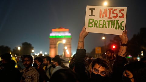 FILE - A person holds a sign during a protest against what they called the government's lack of action to combat air pollution in New Delhi, India, Nov. 9, 2025