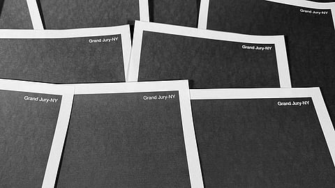 Pages from a totally redacted New York grand jury file into Jeffrey Epstein and Ghislaine Maxwell, released by the US Justice Department, are photographed Friday, Dec. 19, 2025, in Washington.