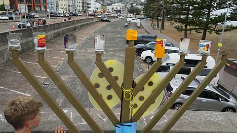 A boy stands near a menorah placed on the bridge at Bondi Beach in Sydney, Sunday, Dec. 21, 2025, after the Bondi shooting took place on Dec. 14. 