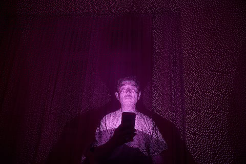 Former Xinjiang government engineer Nureli Abliz, who saw firsthand how surveillance technology flagged thousands of people in China for detention, even when they had committed no crime, is illuminated by cellphone infrared facial recognition beams as he sits for a photo in Mannheim, Germany, where he is currently living in exile, July 23, 2025. 