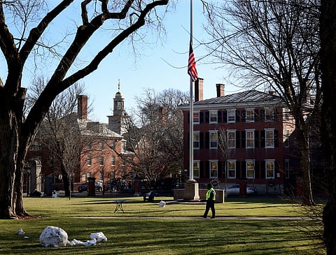 A security guard walks past a flag at half-staff on the main green of Brown University in Providence, RI, Thursday, Dec. 18, 2025,