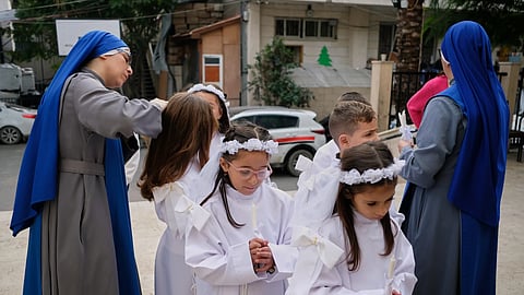Children and nuns gather outside the Holy Family Catholic Church before attending a mass ahead of Christmas celebrations in Gaza City, Sunday, Dec 21, 2025.