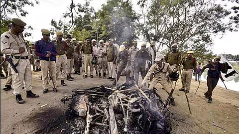 Security personnel look at a damaged bike after a clash between two groups over the issue of eviction at Kheroni in West Karbi Anglong district in Assam on Tuesday