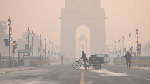 A man pulling a cart crosses Kartavya Path amid dense smog on a cold winter morning in New Delhi.