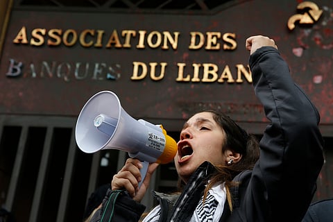  A protester leads a chant during ongoing protests against the Lebanese political class, in front of the building of the Lebanese Association of Banks in Beirut, Lebanon, Thursday, Dec. 26, 2019. 
