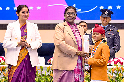 President Droupadi Murmu confers the 'Pradhan Mantri Rashtriya Bal Puraskar' to a recipient during a ceremony on the occasion of 'Veer Bal Diwas'.