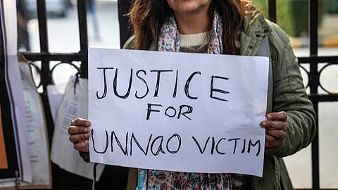 A protester holds a placard during a demonstration against the suspension of the jail term of Kuldeep Sengar, a former BJP MLA who was convicted in the Unnao rape case, outside the Delhi High Court, in New Delhi, Friday, Dec. 26, 2025.