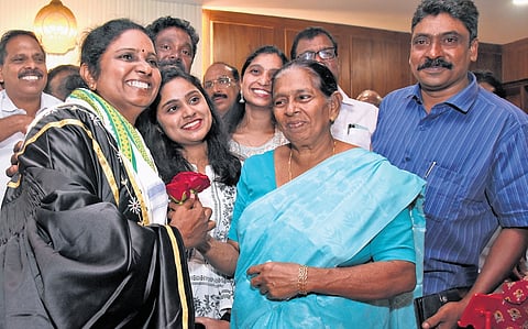 V K Minimol, after taking charge as the new mayor, receives a flower from her mother, Elsy Krishnankutty, and daughters Archana and Anupama 