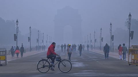 Commuters make their way as a layer of smog engulfs the India Gate during a winter morning at Kartavya Path in New Delhi, Saturday, Dec. 27, 2025.