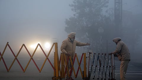 Punjab Police officials set up a barricade amid dense morning fog on a cold winter morning in Amritsar.