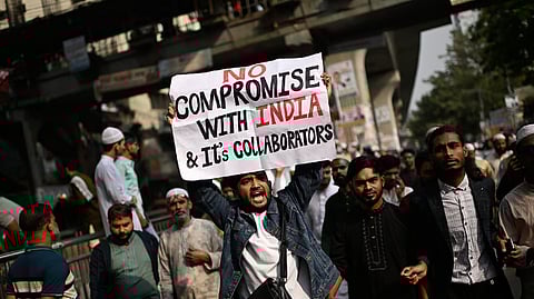 A protester holds a placard and shout slogans during a protest following overnight attacks and vandalism after the death of a prominent activist, who was shot by an assailant a week ago, in Dhaka, Bangladesh, Friday, Dec. 19, 2025. 