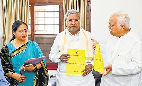 KARC-2 Chairman R V Deshpande presents the report to Chief Minister Siddaramaiah in Bengaluru on Tuesday. Chief Secretary Shalini Rajneesh looks on.