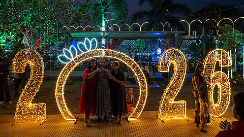 Revellers pose for photographs at an illuminated sea promenade during New Year's Eve in Mumbai on December 31, 2025