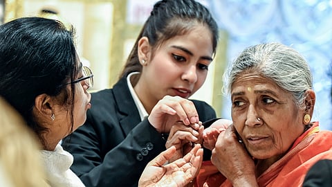 An elderly woman tries on gold jewelry on Dhanteras, at Karol Bagh market, in New Delhi on Tuesday.