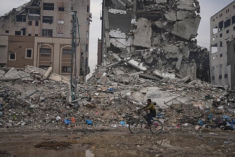 A Palestinian man rides a bicycle past destroyed buildings in Gaza City, Sunday, Jan 4, 2026.
