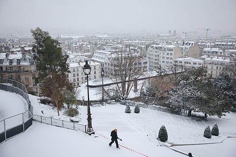 A pedestrian walks at the Square Louise Michel in Montmartre following snowfalls, in Paris, on January 7, 2026.