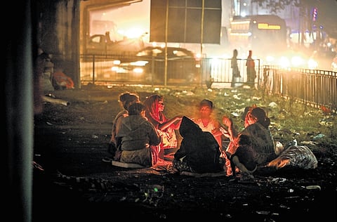A destitute family, living under the Khandagiri flyover, sits around a fire to protect themselves from the bitter cold in Bhubaneswar on Wednesday.