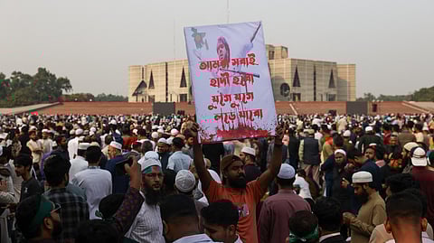 A Bangladeshi mourner holds a poster bearing the portrait of deceased youth leader Sharif Osman Hadi during his funeral in Dhaka on December 20, 2025.