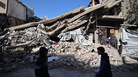 Palestinians walk past the debris of a collapsed house that was previously damaged by an Israeli strike, at the Maghazi refugee camp in the central of Gaza Strip on January 5, 2026.