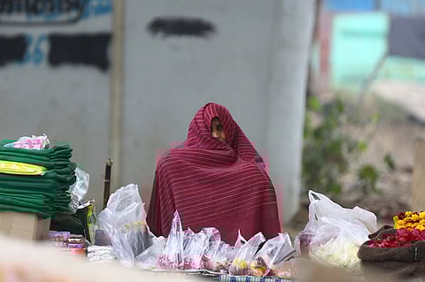 A woman sits wrapped in a blanket on a cold winter morning, in New Delhi 