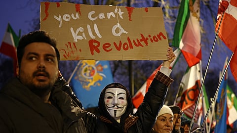 An anti-Iranian regime protester holds up a placard during a gathering outside the Iranian Embassy, central London, on January 9, 2026.