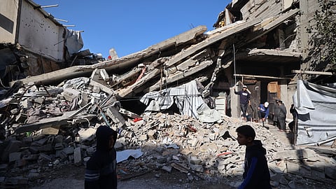 Palestinians walk past the debris of a collapsed house that was previously damaged by an Israeli strike, at the Maghazi refugee camp in the central of Gaza Strip.