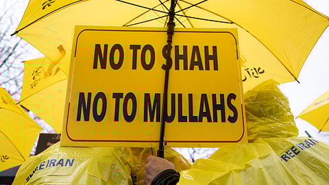 Demonstrators stand under umbrellas and hold signs at Lafayette Park in front of the White House to protest the Iranian government during the "Free Iran" rally on January 10, 2026, in Washington, DC.