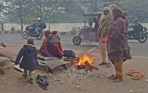 Pavement dwellers and homeless residents huddle around makeshift fires to fend off the biting cold near Okhla in New Delhi 
