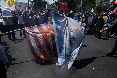 Iranian protestors burn representations of the Israeli and U.S. flags during a protest to condemn Israeli attacks on multiple cities across Iran, after the Friday prayers ceremony in Tehran, Iran, Friday, June 20, 2025. 