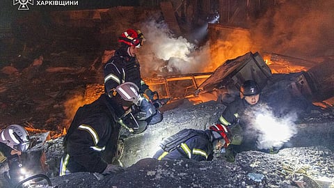 In this photo provided by the Ukrainian Emergency Service, emergency services personnel work to extinguish a fire following a Russian attack in Kharkiv, Ukraine, Tuesday, Jan. 13, 2026.