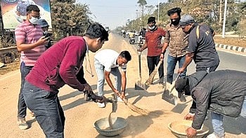 The scribes cleaning the accumulated sand from the Kathajodi river embankment road on Tuesday.