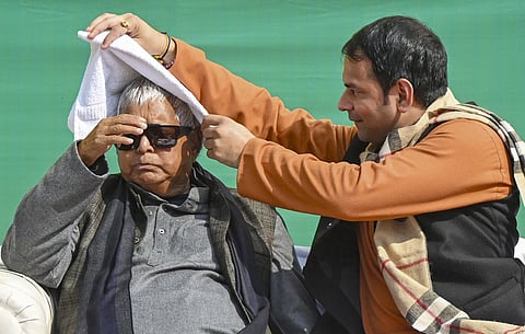 RJD Chief Lalu Prasad Yadav, left, with his son and Jan Shakti Janata Dal President Tej Pratap during 'Makar Sankranti' festival celebration