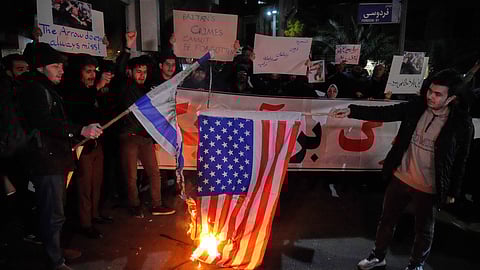 Pro-government protesters burn representations of the US and Israeli flags in front of the British Embassy in Tehran, Iran, Wednesday, Jan. 14, 2026.