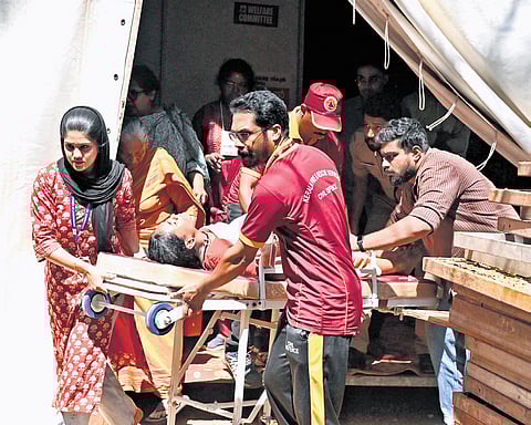 A student being taken to an ambulance for medical care after fainting during a mangalam kali performance.