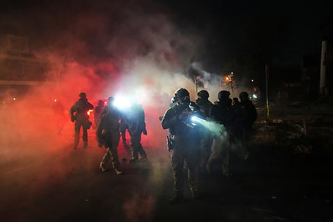 Law enforcement officers stand amid tear gas at the scene of a reported shooting Wednesday, Jan. 14, 2026, in Minneapolis. 