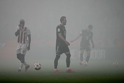 Bayern's Harry Kane, center, walks on the pitch covered in smoke from flares during the German Bundesliga soccer match between 1.FC Koeln and FC Bayern Munich in Cologne, Germany, Wednesday, Jan. 14, 2026.