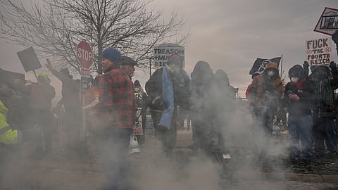 People cover tear gas deployed by federal immigration officers outside the Bishop Henry Whipple Federal Building, Thursday, Jan. 15, 2026, in Minneapolis.