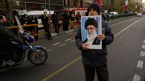 A man holds a poster of the Iranian Supreme Leader Ayatollah Ali Khamenei during a funeral ceremony for a group of security forces, who were killed during anti-government protests, in Tehran, Iran, Wednesday, Jan. 14, 2026.