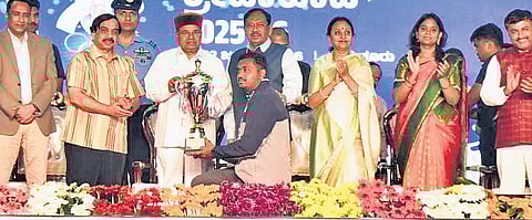 Governor Thaawarchand Gehlot presents the champion trophy to an athlete at the closing ceremony of Karnataka Games at Mahatma Gandhi stadium in Tumakuru on Thursday evening. Home Minister Dr G Parameshwara looks on 