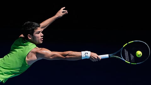 Carlos Alcaraz of Spain plays a backhand return to Corentin Moutet of France during their third round match at the Australian Open tennis championship in Melbourne, Australia, Friday, Jan. 23, 2026. 