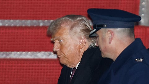 President Donald Trump, left, is greeted by Air Force Col. Christopher M. Robinson, commander of the 89th Airlift Wing, right, after walking down the stairs of Air Force One, upon his arrival at Joint Base Andrews, Md., Thursday, Jan. 22, 2026, after returning from the World Economic Forum in Davos, Switzerland.