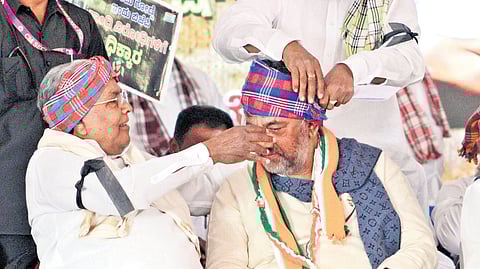 Chief Minister Siddaramaiah helps Deputy CM DK Shivakumar tie a turban during 
a protest against the Centre’s move to replace MGNREGA with VB-G RAM G,  at Freedom Park in Bengaluru on Tuesday  