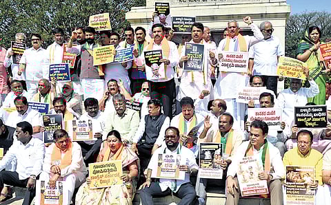 BJP and JDS leaders protest near the Mahatma Gandhi statue on the  premises of Vidhana Soudha in Bengaluru on Tuesday