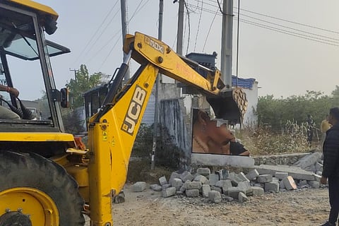 HYDRAA officials removing the illegally constructed compound wall at Kachavani Singaram, restoring the public road to its full width.
