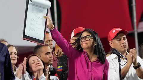Venezuela's acting President Delcy Rodriguez takes part in a rally holding up a copy of a new law after lawmakers approved legislation opening the nation's oil sector to privatization, at the Miraflores Palace in Caracas, Venezuela, Thursday, Jan. 29, 2026.